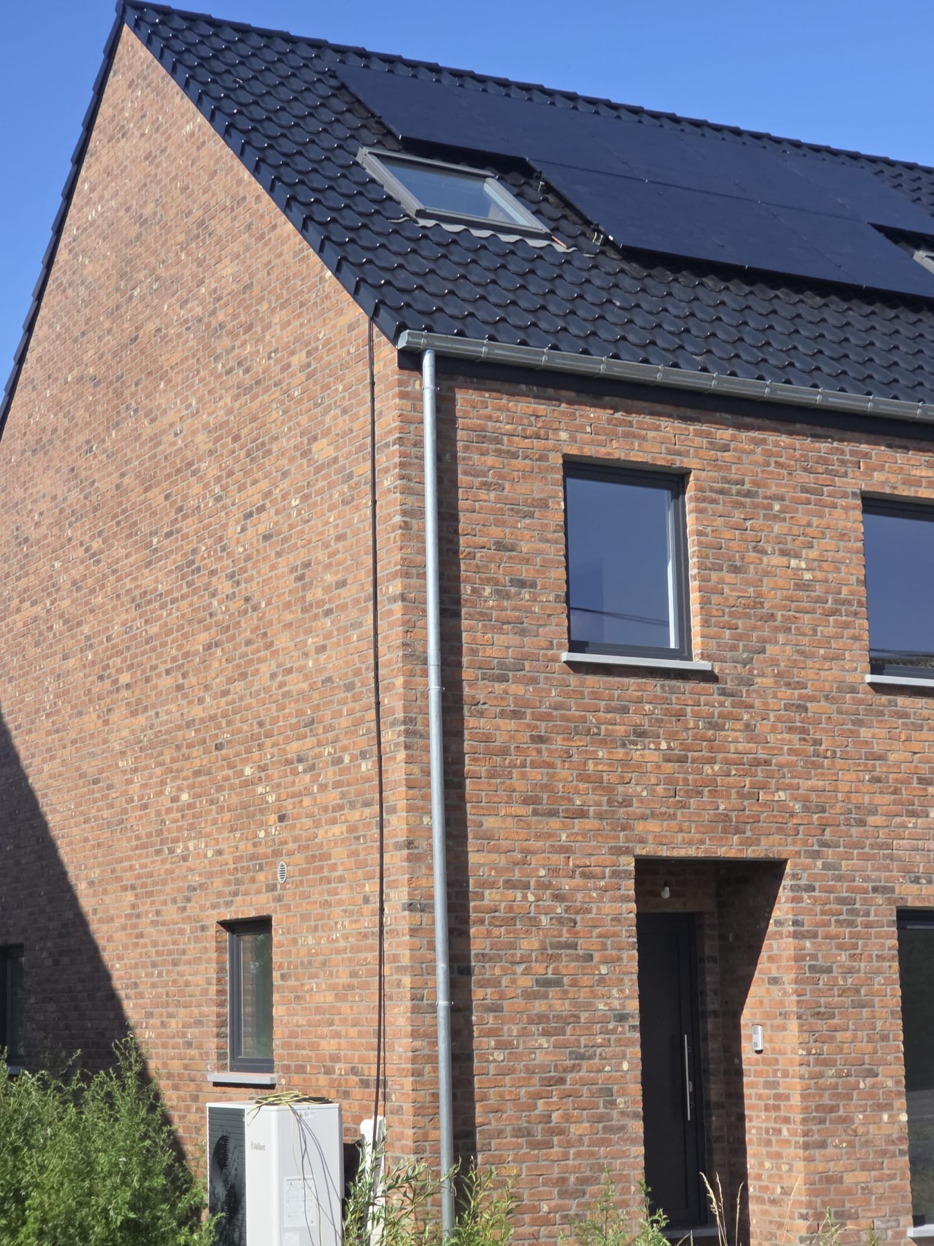 Toiture avec panneaux solaires et unité extérieure de pompe à chaleur en façade